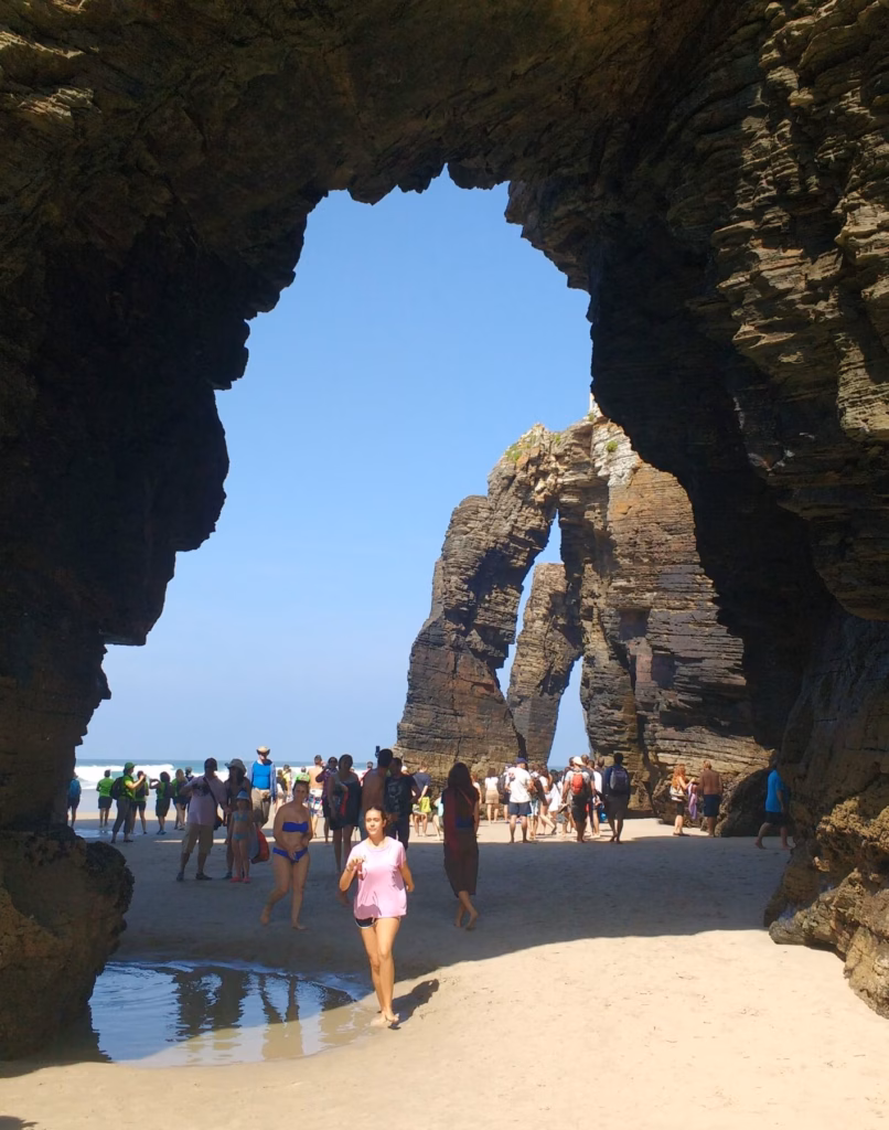 Personas andando por la playa de las catedrales y detalle de los arcos naturales